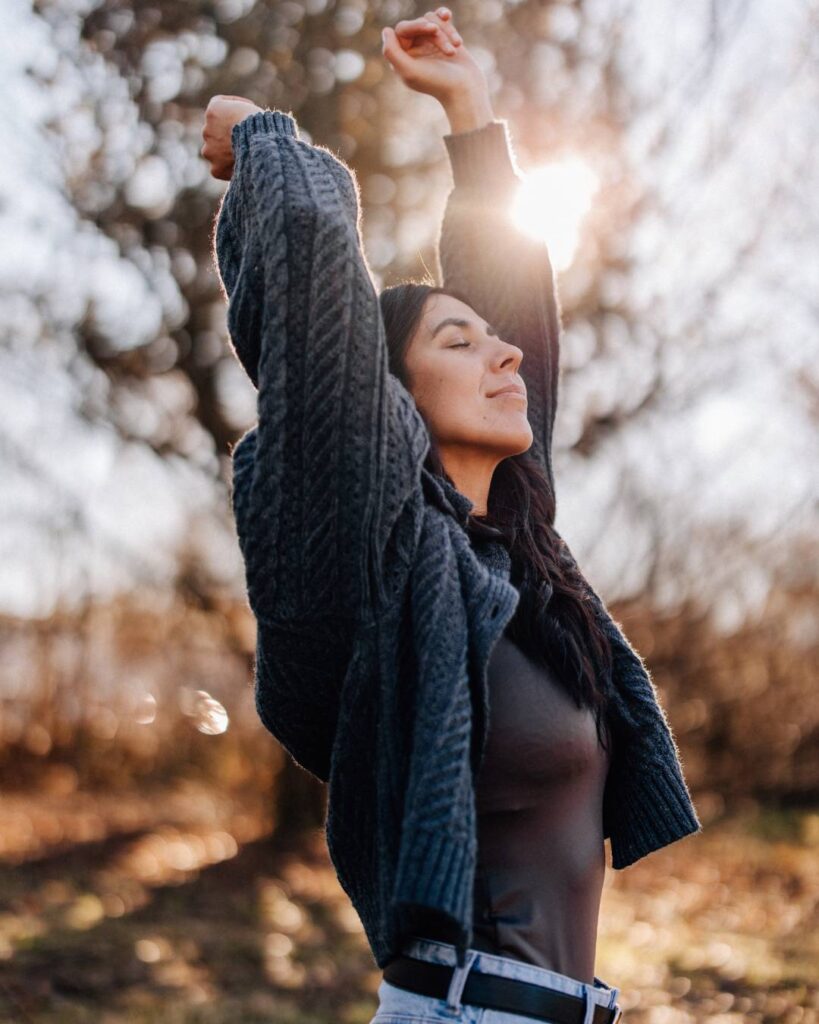 Lisa Schuler mit erhobenen Armen im Sonnenlicht in der Natur